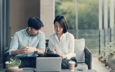 deux collaborateurs assis échangent devant l'ordinateur.