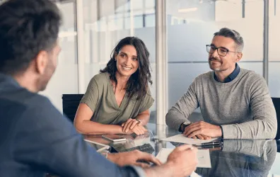 trois collaborateurs discutent en réunion.