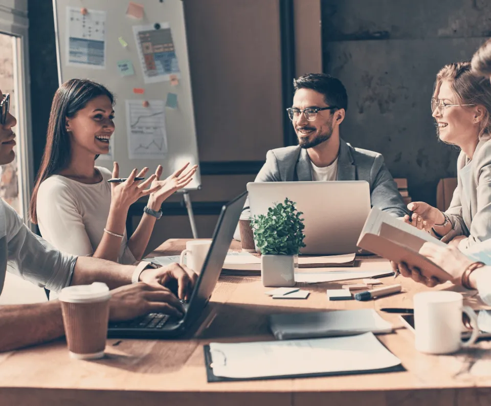 quatre collaborateurs échangent discutent en réunion.